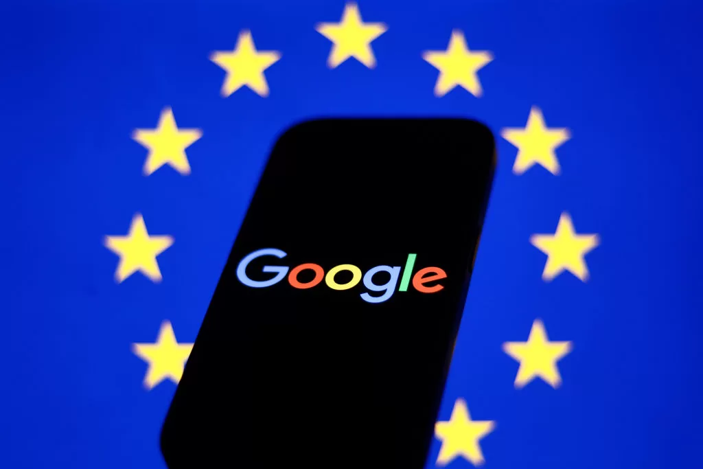 European Union flag displayed on a laptop screen and Google logo displayed on a phone in front of it
