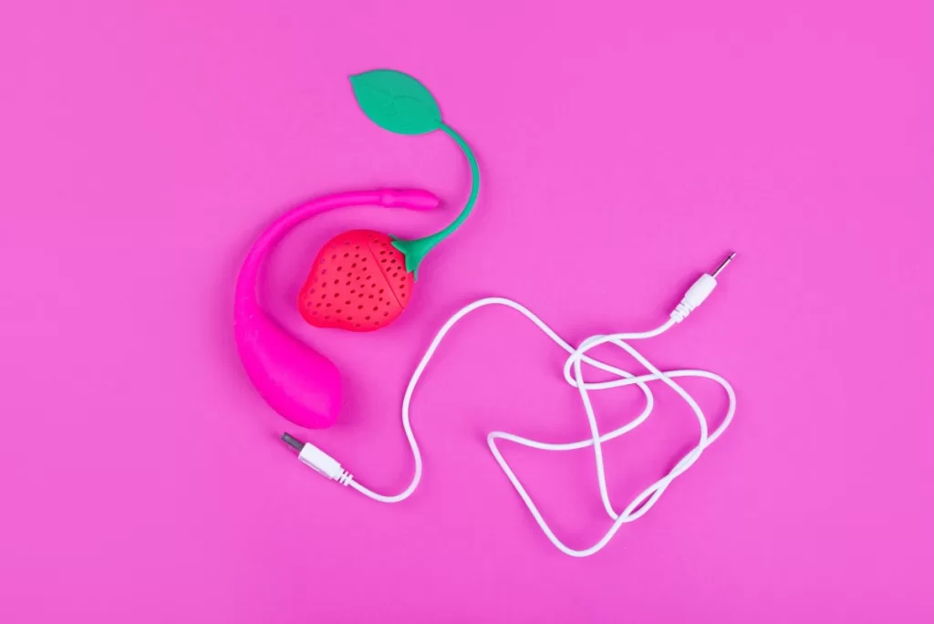 a photo of a female sex toy on a pink background, with a USB cable in the same shot