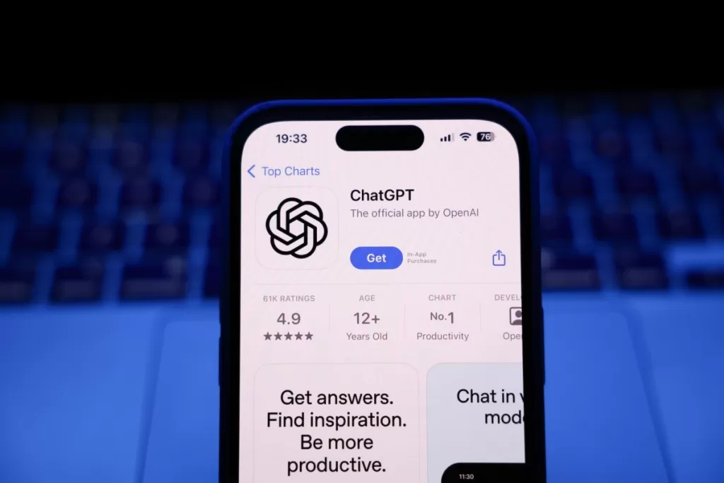A laptop keyboard and ChatGPT on App Store displayed on a phone screen.