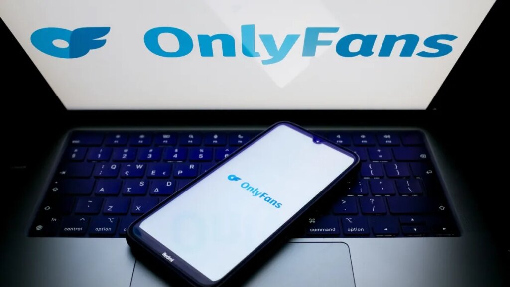 The OnlyFans logo is being displayed on a smartphone screen and on a computer screen